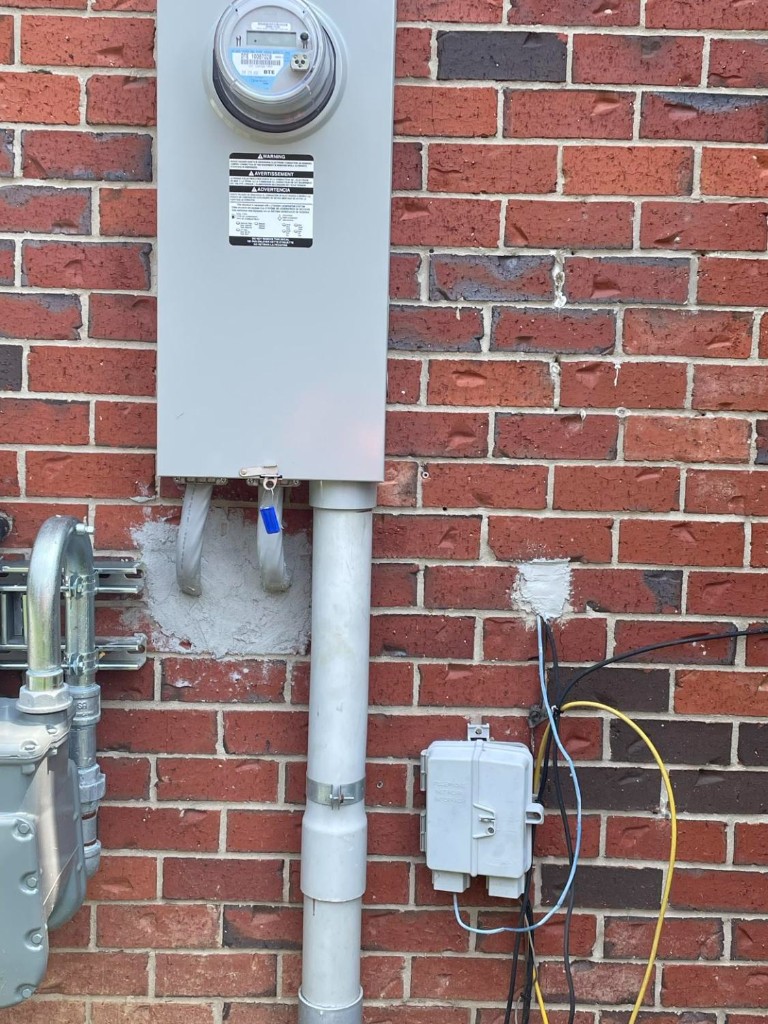 Residential electric meter and service conduit on brick home